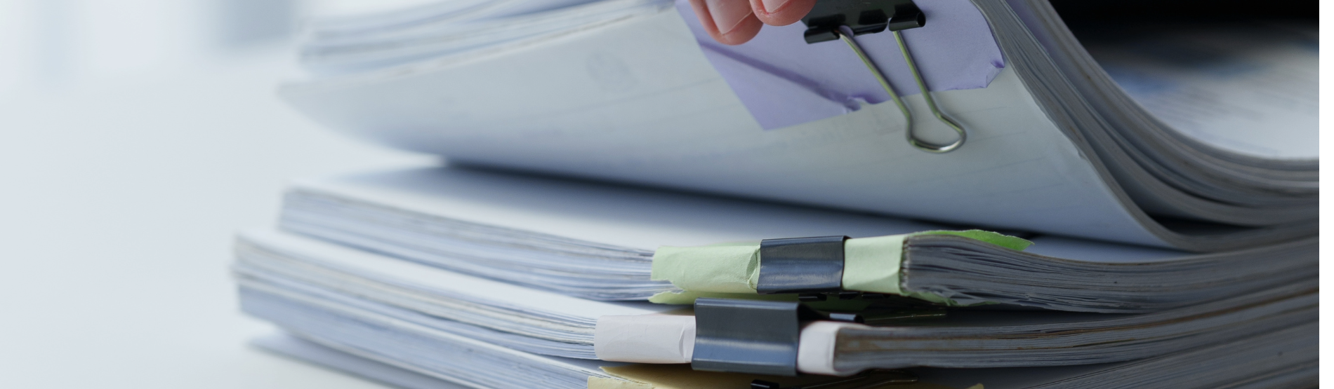 Main prenant un dossier parmi une pile de dossiers.