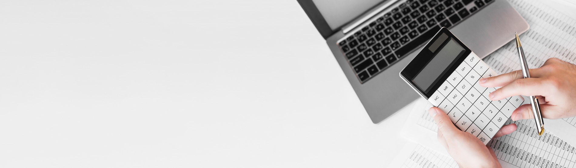 Main tapant sur une calculatrice devant un ordinateur.